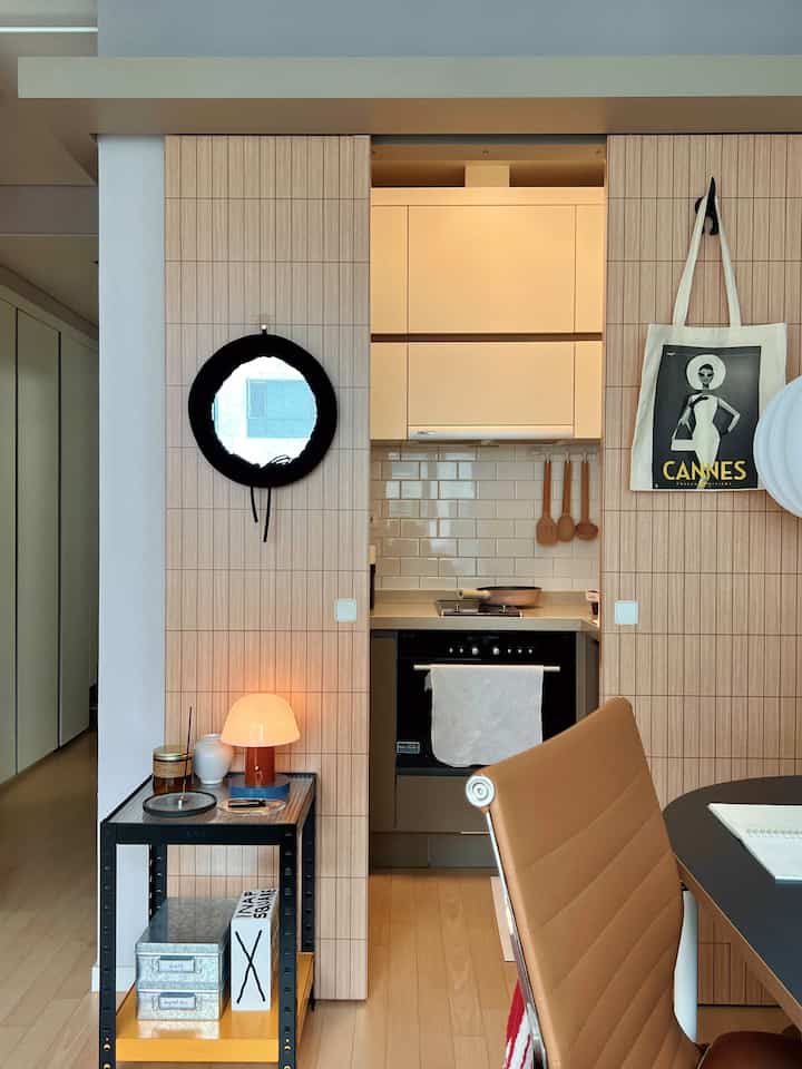 ウッドトーンのミニマルなキッチン、オフィスチェアと多目的キッチンワゴンが配置された雰囲気のあるインテリア