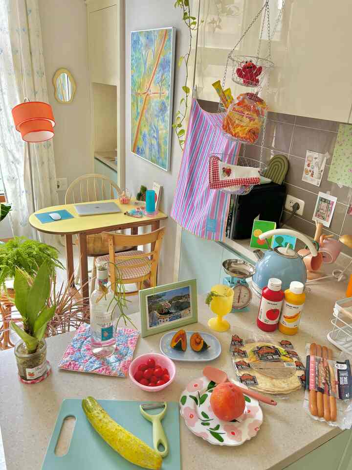 ナチュラルカラーのキッチンとダイニングルーム、黄色いダイニングテーブルと植物が配置された雰囲気のある空間