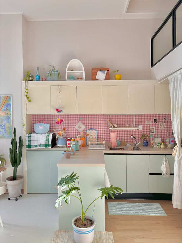 柔らかなピンクとホワイトのトーンのキッチン、収納アイデアと自然の植物が調和した温かみのあるインテリア