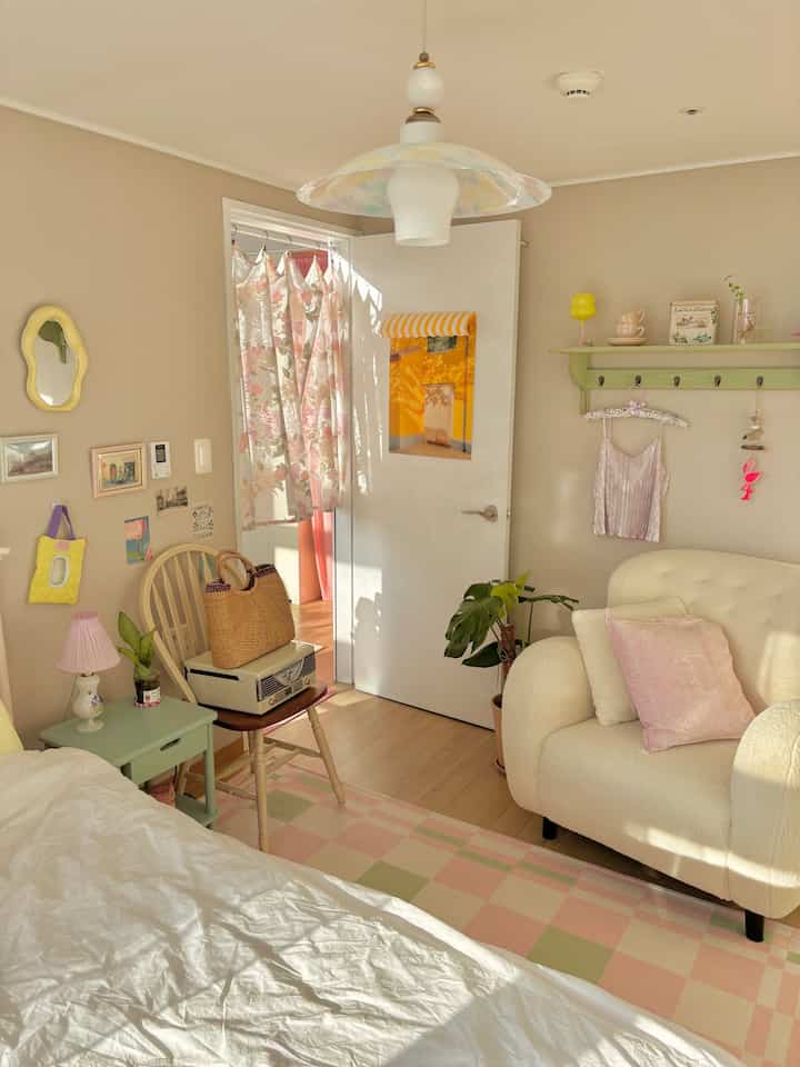 暖かいベージュとウッドトーンの寝室、ベッドとクリーム色のアームチェアが配置された居心地の良い空間