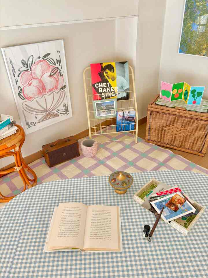 ナチュラルカラーのリビング、ポスターとチェック柄のテーブルに本や小物が置かれた雰囲気のあるインテリア