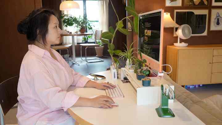 木目調の壁と白い半円形のデスクが配置されたリビングのホームオフィス空間