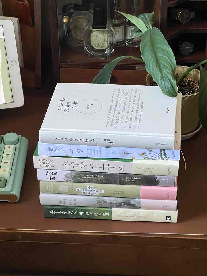 ブラウンの木製デスクの上に本と植物が置かれた居心地の良いホームオフィスの読書空間