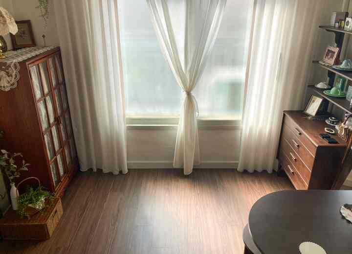 ベージュと木目調の調和があるダイニング、ヴィンテージ風の木製家具と白いカーテンが配置された雰囲気のあるインテリア