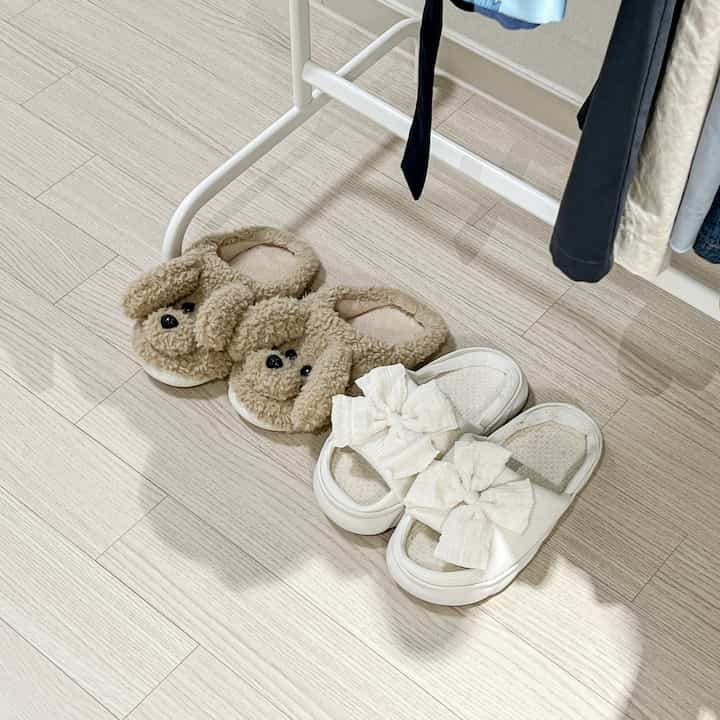 アイボリーとナチュラルカラーのキッチンの床に、犬とリボンの形のスリッパがきちんと並べられた印象的な空間