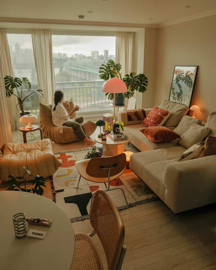 ベージュと木目調のリビング、居心地の良いソファとアームチェア、多様なテーブルランプが温かみのある雰囲気を作る空間