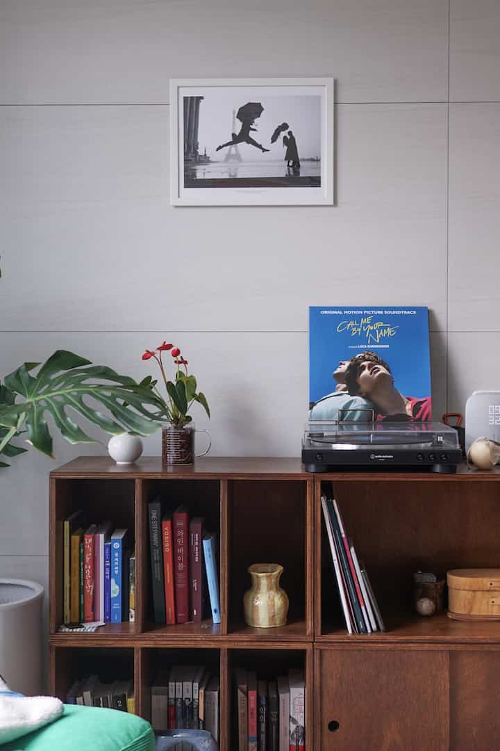 茶色の木目調の本棚の上にターンテーブルとLP、調和のとれた植物が配置された雰囲気のある空間