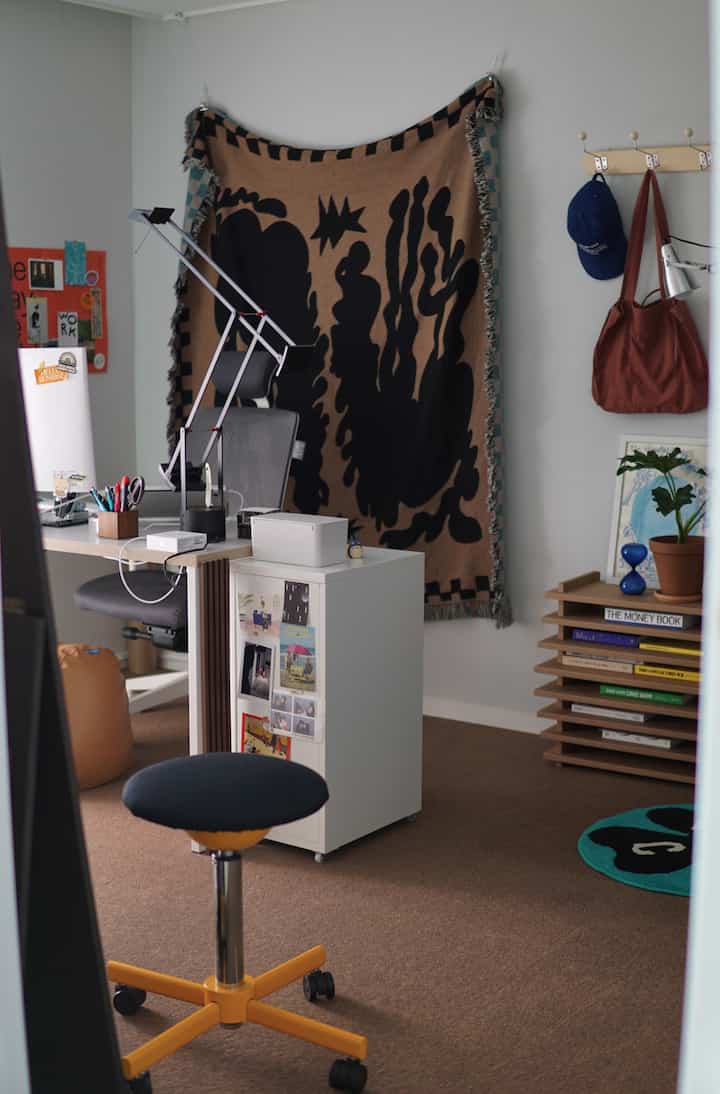 柔らかいブラウンのカーペットと白いデスク、チェストが配置されたモダンなホームオフィスの雰囲気ある空間