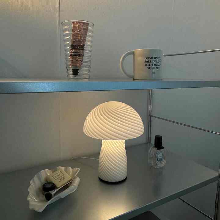シルバーの金属棚に配置されたムードライト型のキノコランプとマグカップ、多様なオブジェが配されたミニマルなインテリア
