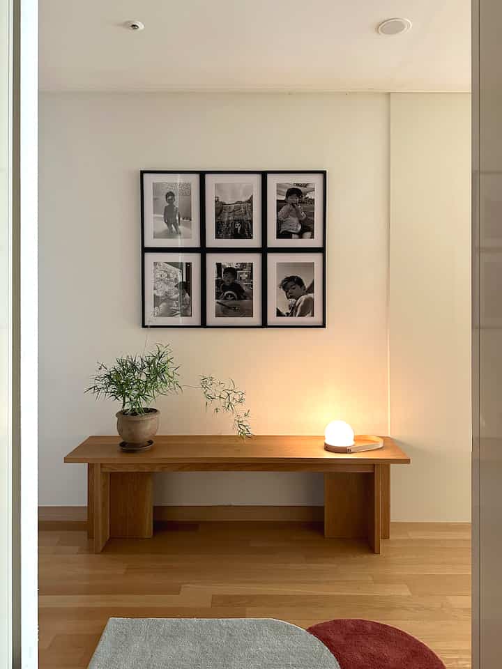 木目調の床とベンチがある白い玄関、子供の写真額とテーブルランプが配置された落ち着いた雰囲気のインテリア