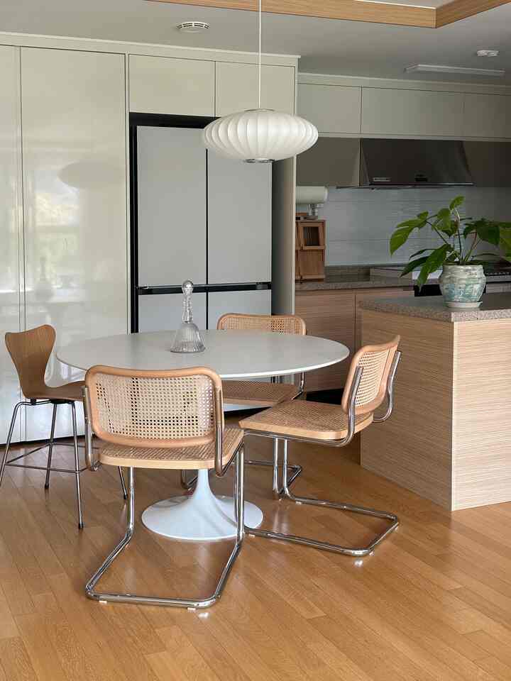 白と茶色のトーンが調和するナチュラルモダンのダイニングルーム、楕円形のダイニングテーブルとラタンチェアが配置された落ち着いた空間