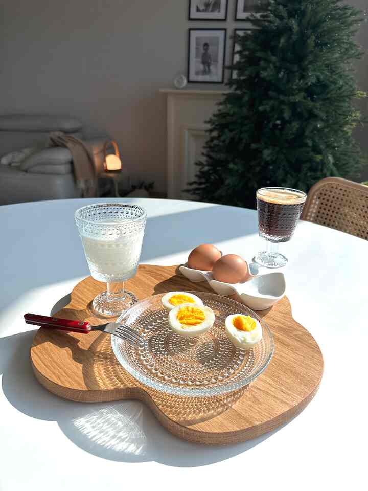 白と木目調が調和したダイニングスペース、ガラスとゆで卵が配置された雰囲気のあるおうちカフェのテーブル