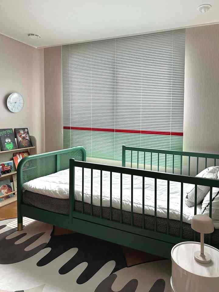 緑色の子供用ベッドとミント色のブラインドが特徴の子供部屋、赤いアクセントのある落ち着いた雰囲気のインテリア
