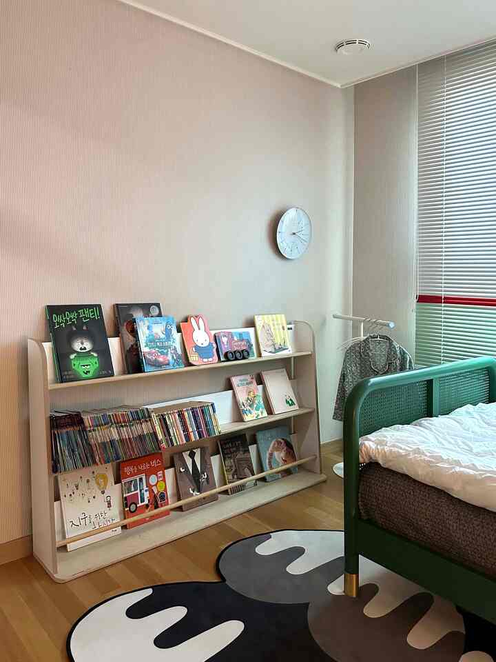 ナチュラルな色調とグリーンが調和した子供部屋、書棚とベッドが配置された暖かみのあるインテリア