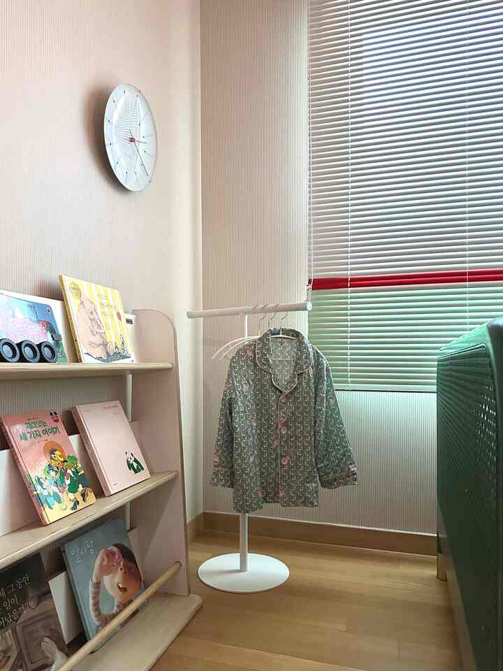 白とベージュの色調の子供部屋、低いT字型ハンガーと本棚が配置された落ち着いた雰囲気のあるインテリア
