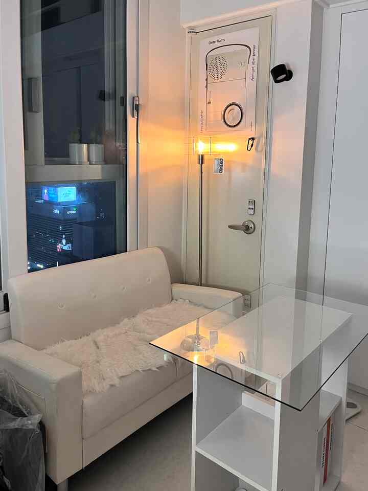 暖かい照明と白い家具が配置された二人用ソファのあるアパート玄関スペース