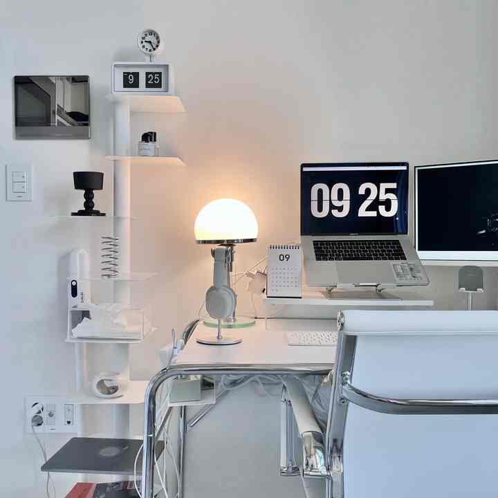 白を基調としたミニマルなホームオフィス、整理されたデスクとモニター、オフィスチェアが配置された空間