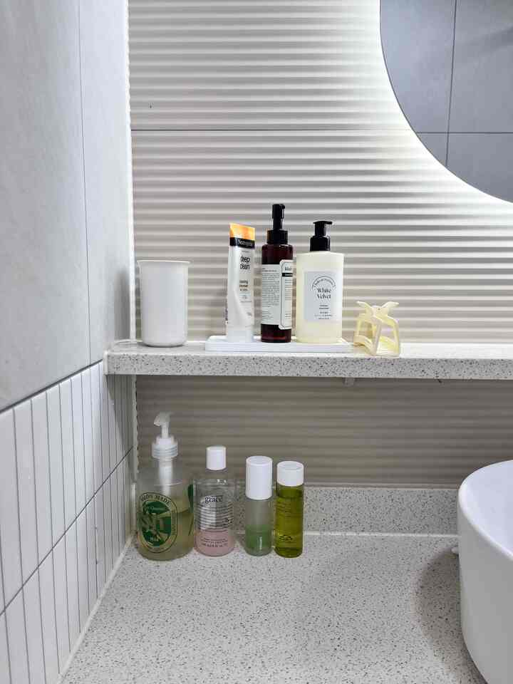 ホワイトトーンのバスルーム化粧台、様々なスキンケア製品が整然と並べられた清潔感のあるインテリア