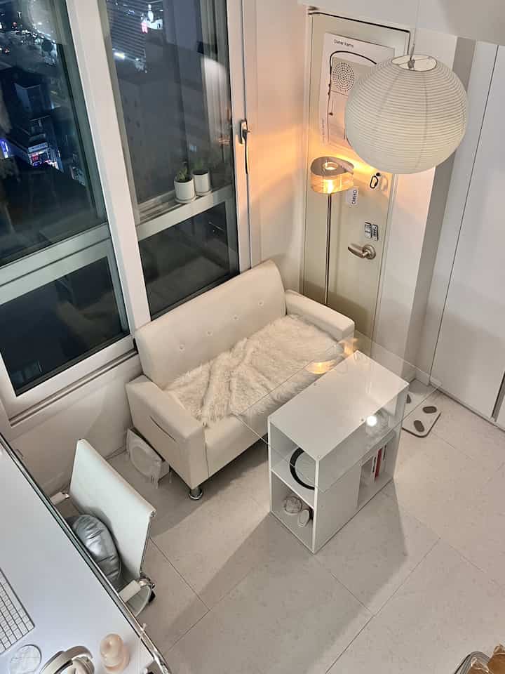 白を基調としたモダンなリビング、ソファとフロアランプが配置された雰囲気のある空間