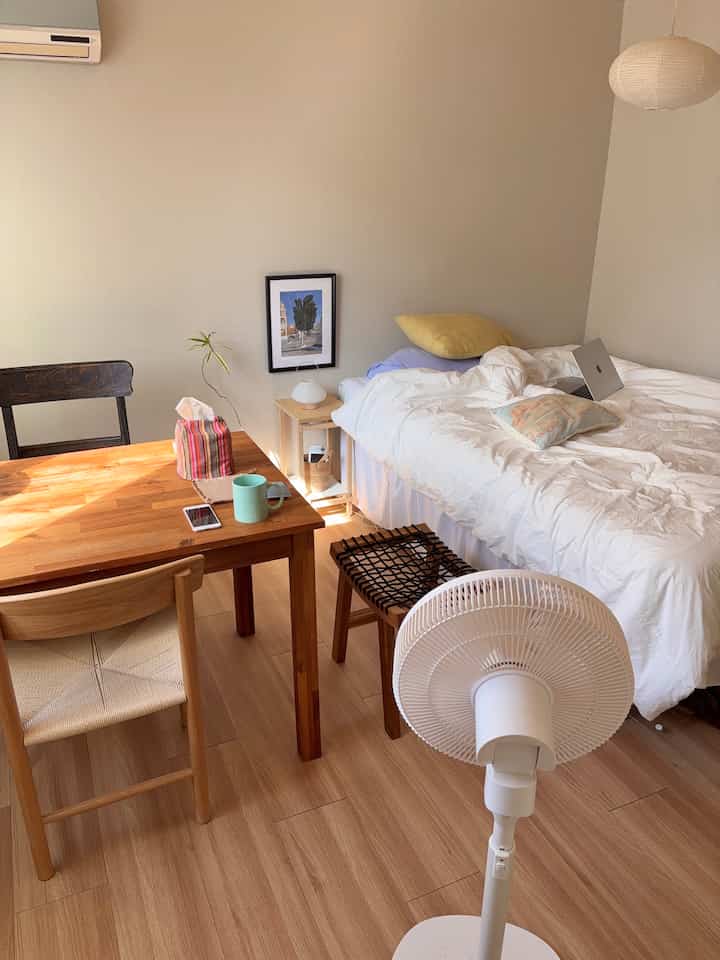 ホワイトと木目調のナチュラルな寝室、広々としたベッドとテーブル、ナイトテーブルが温かみのある雰囲気を演出する空間