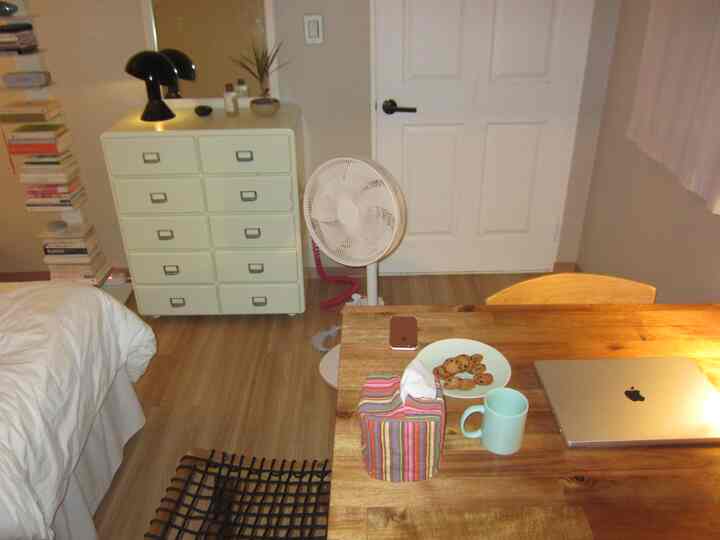 白とナチュラルウッド調の調和が取れた一人暮らし向け寝室、シンプルなデスクと収納棚が配置された落ち着いた空間