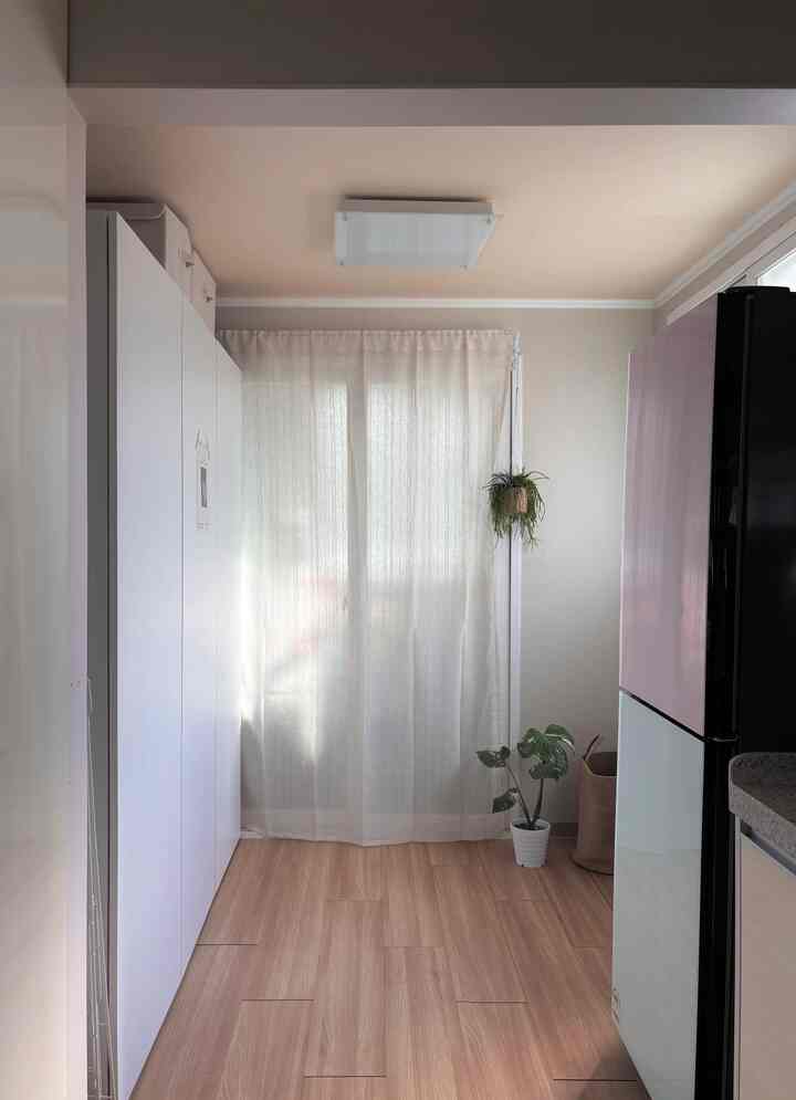 白と木目調の調和した小さなウォークインクローゼット、大きなワードローブとピンクの冷蔵庫が空間を構成し、清潔感のある雰囲気を演出