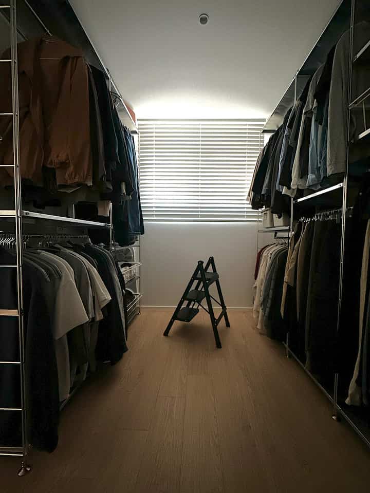 木目調の床と白い壁、ステンレス棚やハンガーが配置されたすっきりとしたウォークインクローゼットの空間