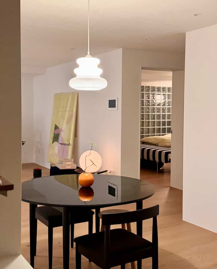 白い壁と天井、黒のラウンドダイニングテーブルと椅子が配置されたシンプルでナチュラルなダイニングルーム