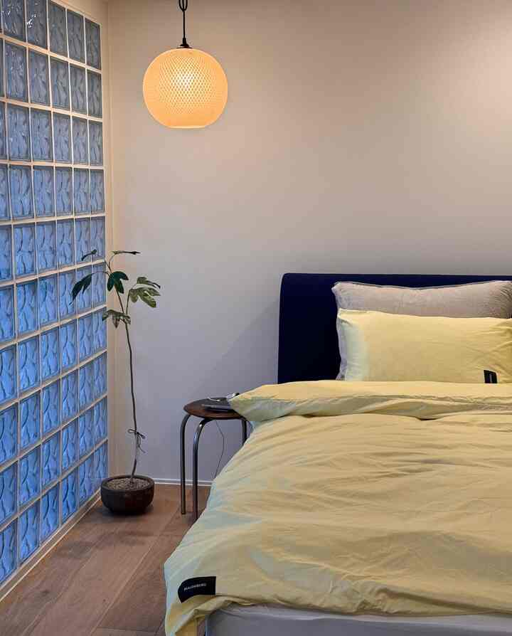 ナチュラルな木目調の床と黄色い寝具が配置されたモダンな寝室のインテリア