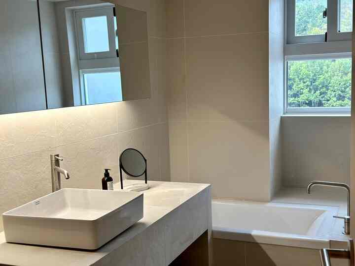 白を基調としたバスルーム、清潔感ある洗面台とバスタブが配置されたシンプルな空間