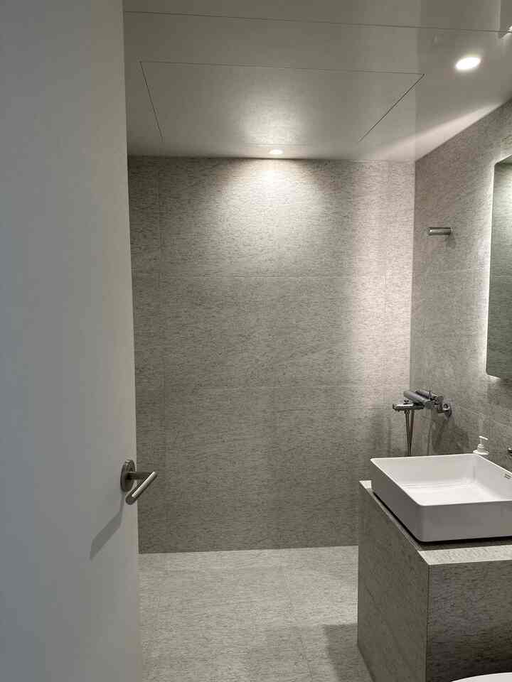 グレー調のシンプルでミニマルなバスルーム、直線的な洗面台と滑らかなタイルが配置された清潔感のあるインテリア