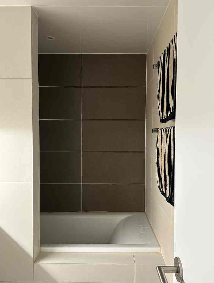 ホワイトとベージュのトーンで構成された埋め込み浴槽のあるバスルーム、清潔感とシンプルさが感じられる空間