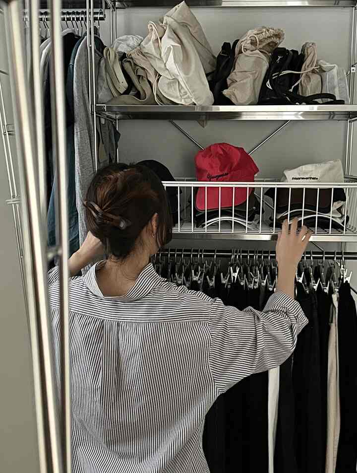 ナチュラルトーンのクローゼット収納スペース、人が服を整理している印象的な空間