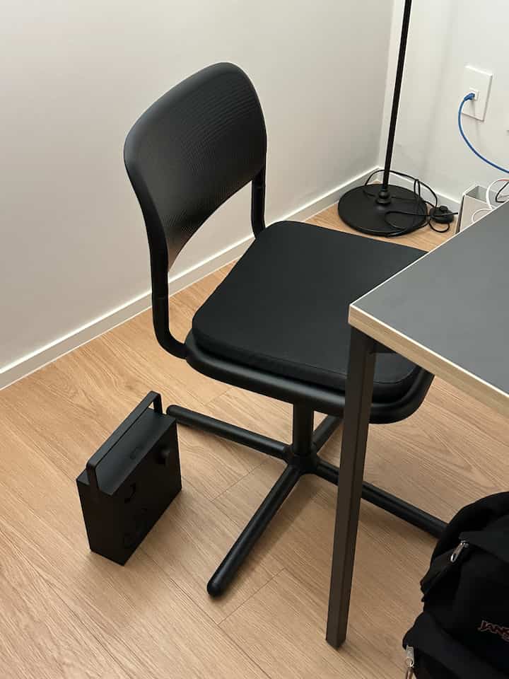 ブラックと木目調の色合いが調和したコンパクトなホームオフィス、イケアの回転椅子とデスク、Bluetoothスピーカーが配置された実用的なインテリア