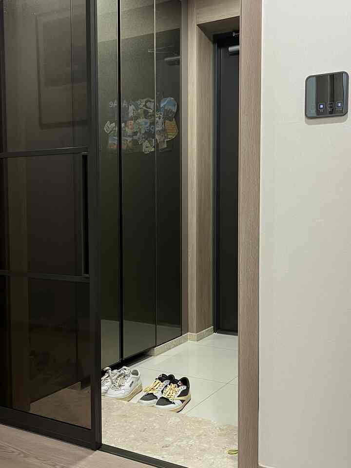 白いタイル床と黒い引き戸がある清潔な玄関空間、木目調のドア枠でアクセントをつけたモダンなインテリア