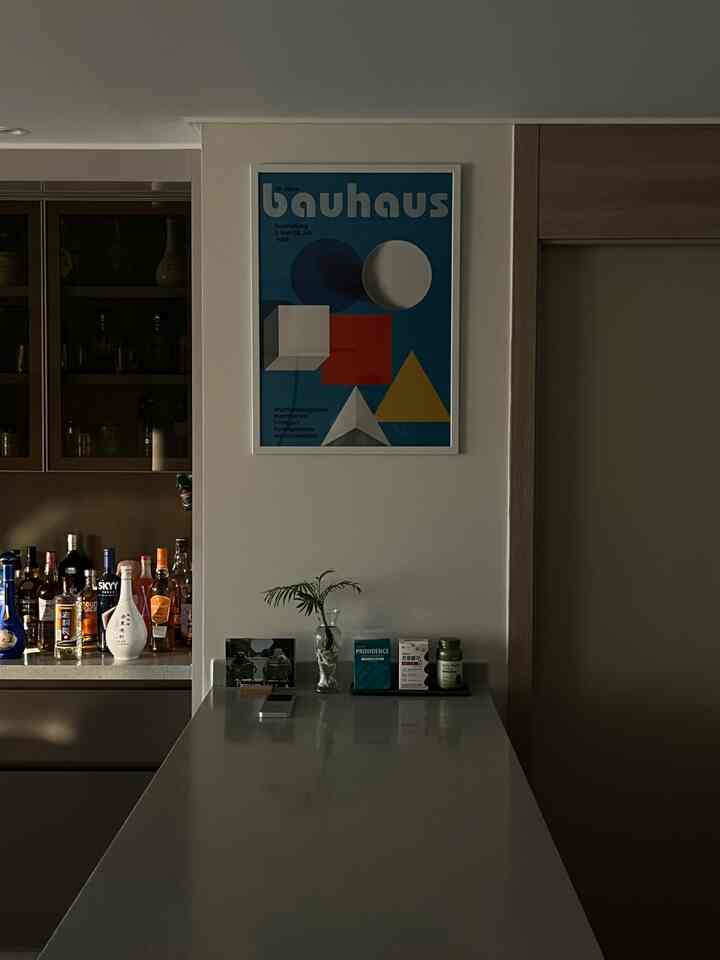 白とベージュのトーンのモダンなキッチン、長く伸びたキッチンアイランドとホームバー風の壁棚が配置された空間