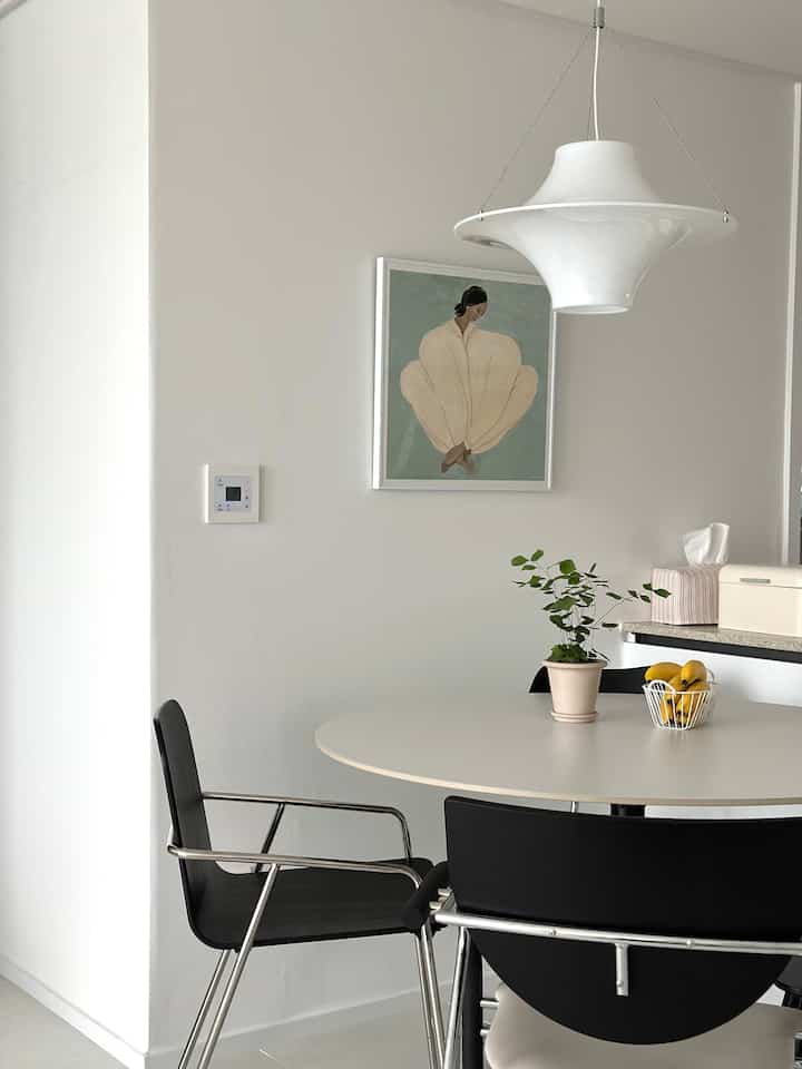 ホワイトとブラックのトーンのリビングダイニング、円形のダイニングテーブルとペンダントライトが配置されたモダンでシンプルな雰囲気のインテリア