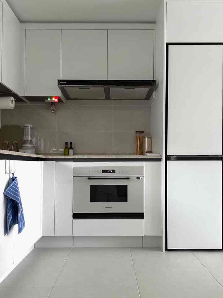 ホワイトとグレーのモダンなキッチン、すっきりとした収納とサムスン電子製オーブンが配された空間