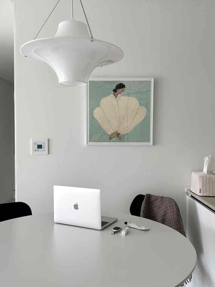 白を基調としたコンパクトなダイニング、中央にモダンな円形ダイニングテーブルと壁のアートが配置されたシンプルなインテリア