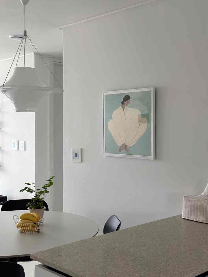 ホワイトとグレーのトーンでまとめられたキッチンとダイニングスペース、丸テーブルとモダンな椅子が配されたミニマルなインテリア