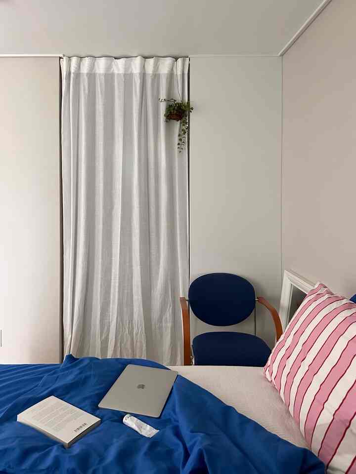 白とネイビーの調和が取れた子供部屋、カーテンと心地よいベッドが配置された温かみのあるインテリア