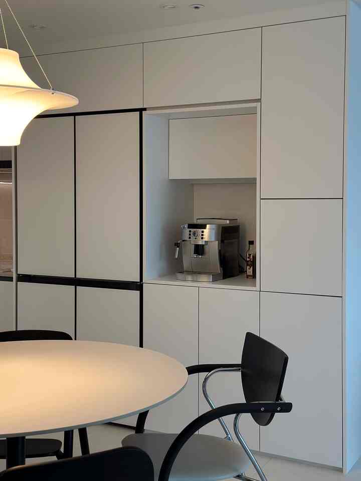 白と黒のトーンのキッチン、丸いダイニングテーブルとペンダントライトが配置されたモダンで清潔感のあるインテリア