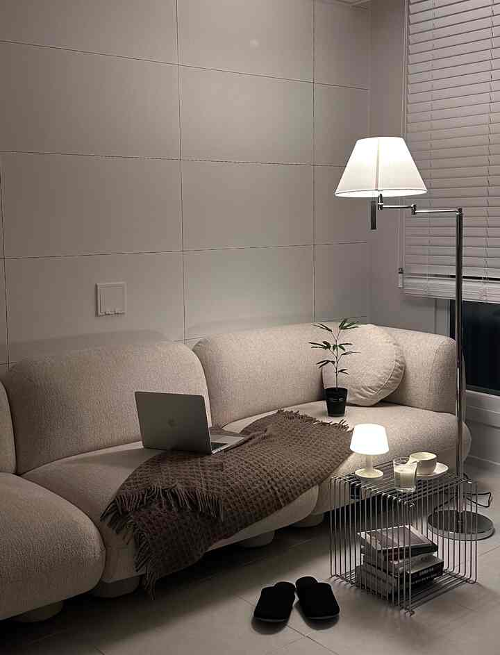 ホワイトとベージュの色調のリビング、ベージュのソファとフロアランプが配置された居心地の良いムードのあるインテリア