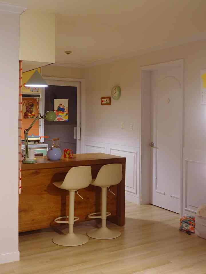 ウッドトーンのキッチンアイランドとベージュのカウンタースツールが配置された居心地の良いコンパクトなキッチンスペース