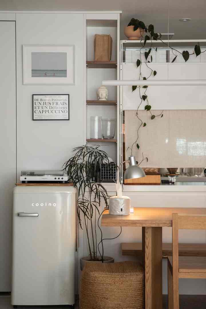 ウッディとヌーディトーンのキッチンスペース、クリーム色のレトロ冷蔵庫とつる植物が調和したナチュラルな雰囲気