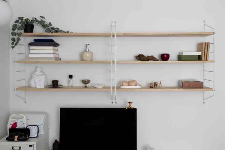 ナチュラルな色調の書斎、壁棚にオブジェが配置された整ったホームオフィス空間