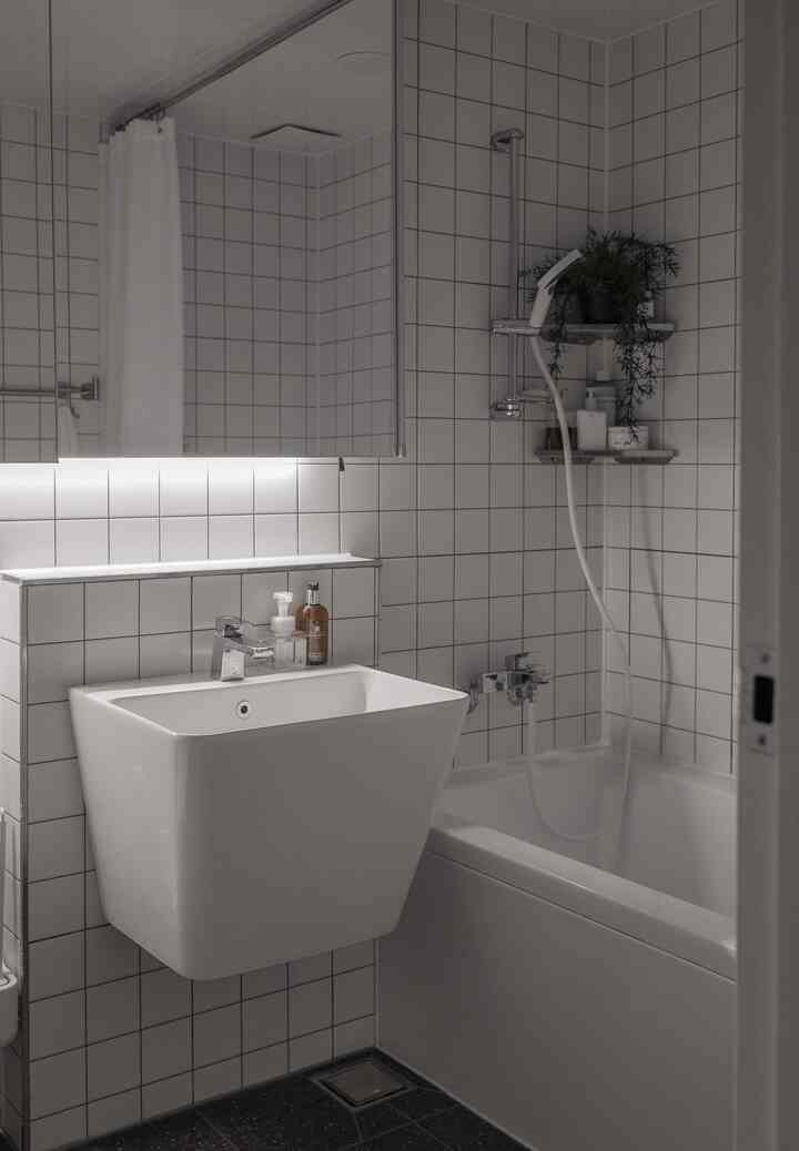 白いタイルと洗面台、浴槽が配置されたモダンなバスルームのインテリア