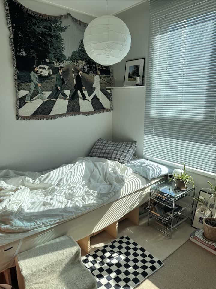 白とナチュラルトーンの寝室、低くてシンプルなベッドとブラインドが配置された雰囲気のある空間