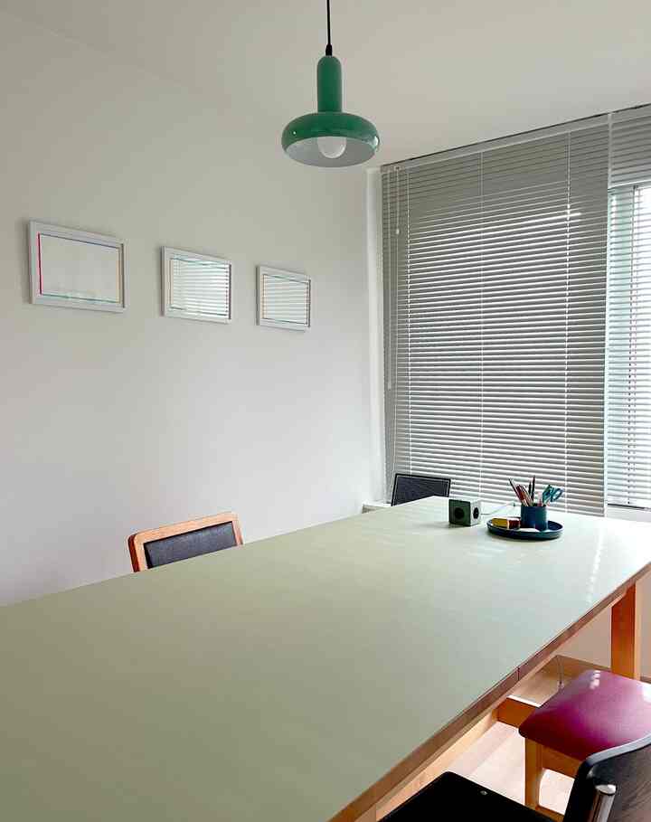 白い壁とグレーのブラインドがあるダイニングルーム、大きなダイニングテーブルと椅子が配置された清潔でナチュラルな雰囲気のインテリア