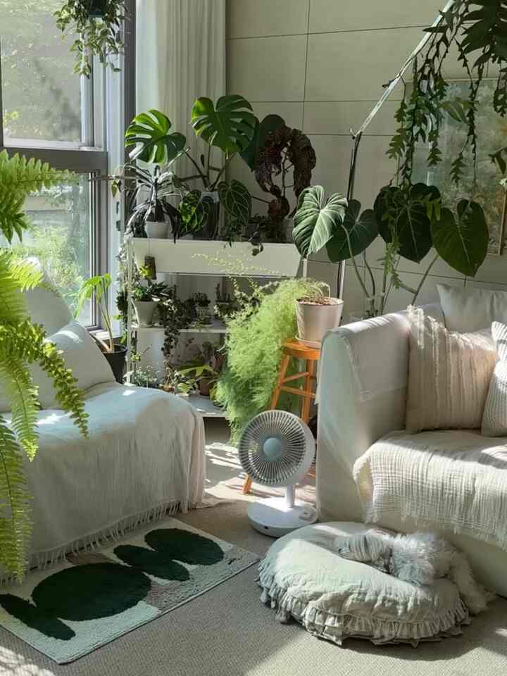 白と緑のリビングルーム、L字型のソファと豊富な植物が配置された自然で居心地の良いインテリア